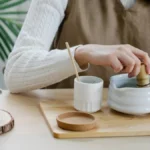 A dark wood table with a steaming Puer tea cup and a frothy iced matcha latte under soft golden light.