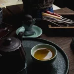 Aged pu'er tea leaves unfurling in a clay teapot with steam rising under warm golden light.