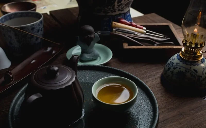Aged pu'er tea leaves unfurling in a clay teapot with steam rising under warm golden light.