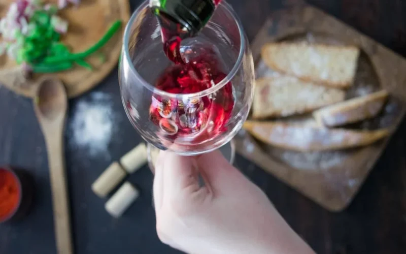Clear 0% rosé wine poured into stemmed glass under soft golden lighting in minimalist kitchen with greenery.