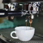 Superautomatic espresso machine steaming as barista prepares coffee in modern kitchen.