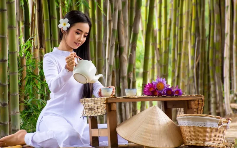 A steaming porcelain pu'er tea cup on a bamboo tray under soft natural light.