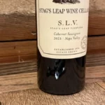 A dark purple wine glass with swirling liquid under candlelight near an oak barrel.