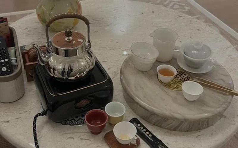 Gong fu tea ceremony in a Southern home with steaming cups and gathered guests during Lunar New Year.