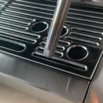Steam wand shows iridescent oxidation residue under studio lighting on stainless steel surface.
