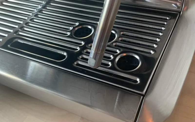Steam wand shows iridescent oxidation residue under studio lighting on stainless steel surface.