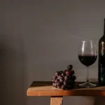 Aged tawny port wine bottle on rustic table with dried grapes and elegant label.