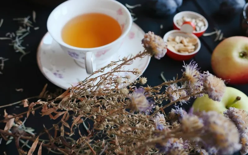 Golden tea leaves steeping in porcelain cup with steam rising under warm lighting.