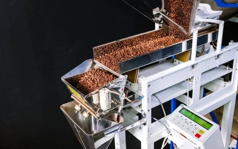 Thermocouple probe in coffee roaster with digital displays and tools on wooden work surface.