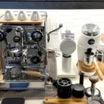 Two coffee grinders placed next to each other on a marble countertop with soft morning light reflecting on their surface