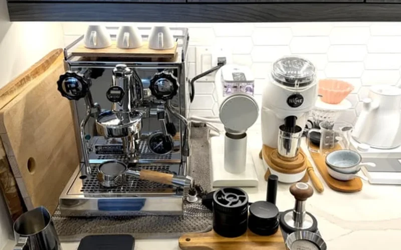Two coffee grinders placed next to each other on a marble countertop with soft morning light reflecting on their surface