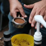 Barista tamping portafilter in modern coffee shop with ambient lighting.