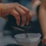 Barista brewing cold coffee with ultrasonic technology in a modern café setting.