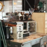Brutalist styled coffee bar with espresso machine and steam rising from dark roast coffee.