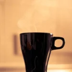 A steaming coffee cup with rich crema under soft natural light in a minimalist kitchen setting.