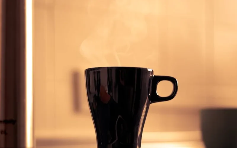 A steaming coffee cup with rich crema under soft natural light in a minimalist kitchen setting.
