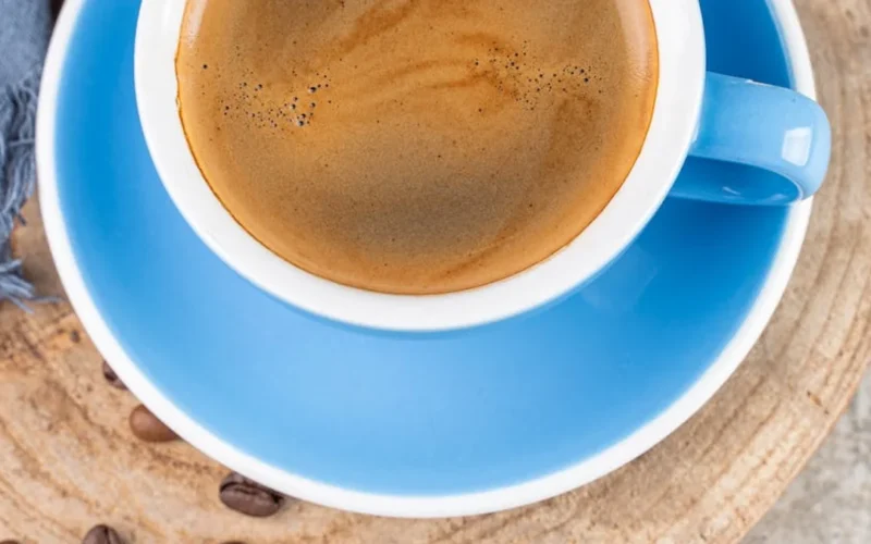Espresso pouring into cappuccino cup with steam and natural light.