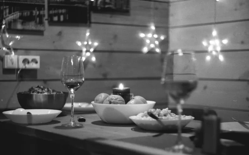 A narrow rimmed wine glass reflecting candlelight in a dimly lit room with soft shadows and golden light.