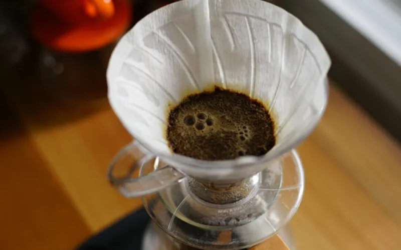 Artisanal borosilicate pour over coffee brewing setup with steam rising under soft lighting.