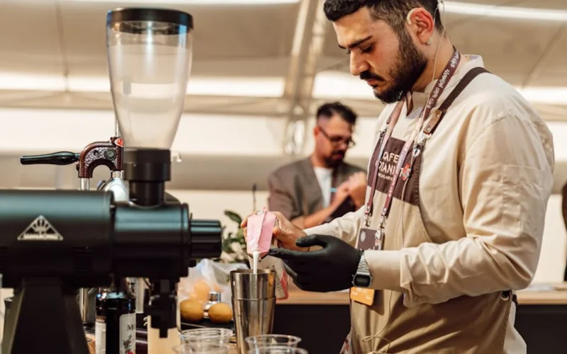 Barista adjusts digital coffee grinder interface in modern café setting.