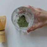 A traditional Japanese tea ceremony with a matcha bowl and bamboo whisk under soft lighting.