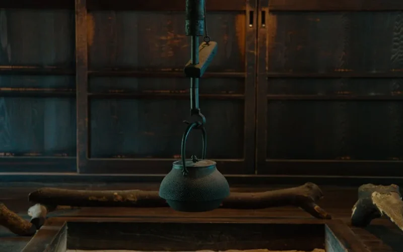 A clay teapot steaming with puer tea on a bamboo tray in a traditional Chinese tea room with soft lighting.