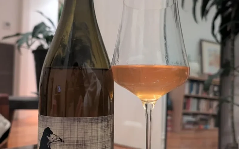 Pale white wine in a glass accompanied by lemongrass and makrut lime leaves.