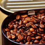 Clear glass carafe filled with dark cold brew coffee surrounded by roasted coffee beans.