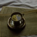A steaming clay gaiwan with dark tea liquor, surrounded by dried leaves and bamboo, under soft natural light.
