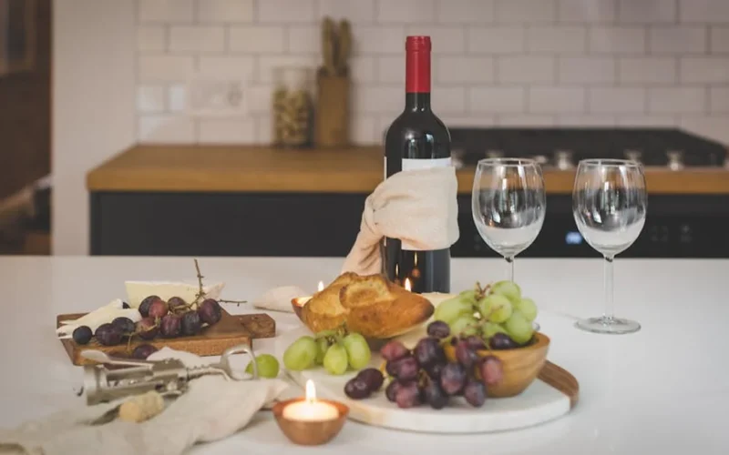 Decanted Bordeaux wine in crystal glass under candlelight on a wooden table with wine bottles and tasting notes.