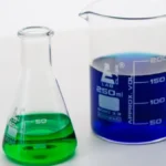 Raw green coffee beans placed beside scientific glassware and a digital chemical fingerprint map.