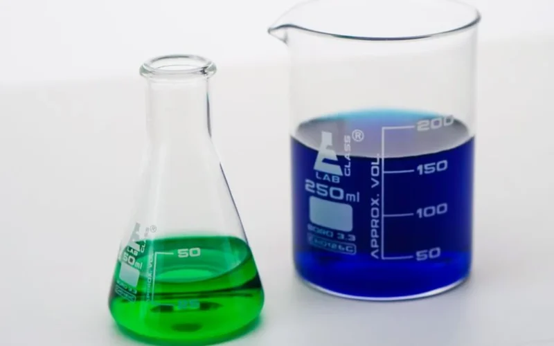 Raw green coffee beans placed beside scientific glassware and a digital chemical fingerprint map.