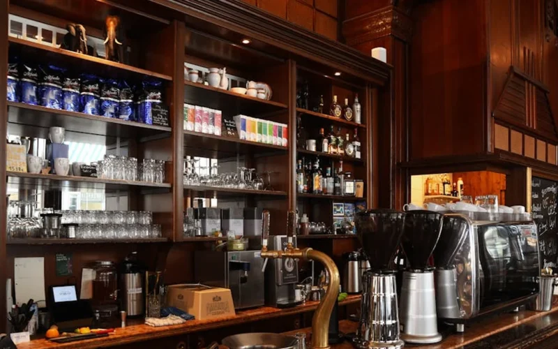 Modern coffee machines creating latte art with steaming milk in a bright café setting.