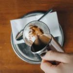 Close up of dark espresso being poured over ice cubes in glass