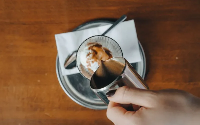 Close up of dark espresso being poured over ice cubes in glass
