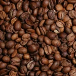 Roasted coffee beans scattered over official regulatory documents and a pen on a wooden desk.