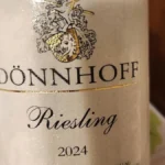 Close-up of a chilled glass of Riesling wine in a sunny vineyard setting.