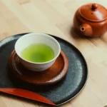 Vintage tea canister with puerh leaves and traditional tea tools under warm lantern light.