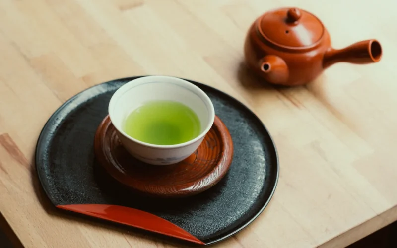 Vintage tea canister with puerh leaves and traditional tea tools under warm lantern light.