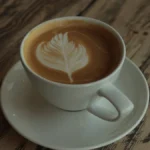 Artisanal coffee cup with steam rising on rustic wooden table under warm natural light.