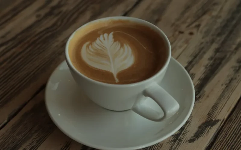 Artisanal coffee cup with steam rising on rustic wooden table under warm natural light.