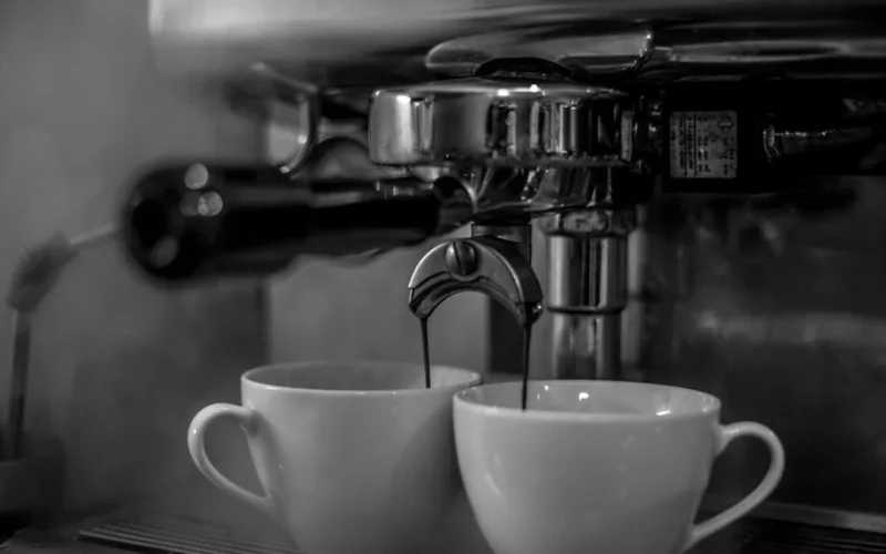 A steaming dark espresso cup in a traditional Italian café with sunlight reflecting on bar tools.