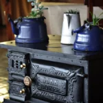 Dark roasted coffee beans spilling from a cast iron roaster with steam rising and golden light from a kitchen window.