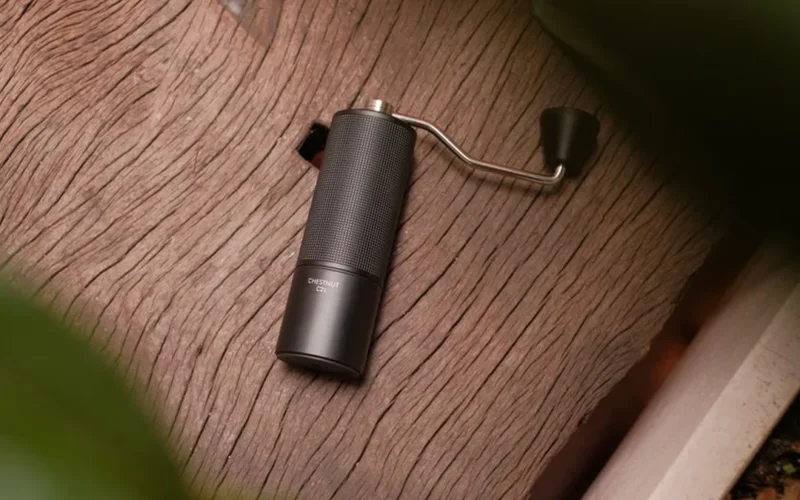 High-end coffee grinder in modern kitchen setting with precise coffee grounds spilling into glass container.