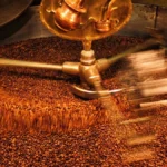 Close-up of a large, vintage industrial coffee roasting machine in a dimly lit warehouse.