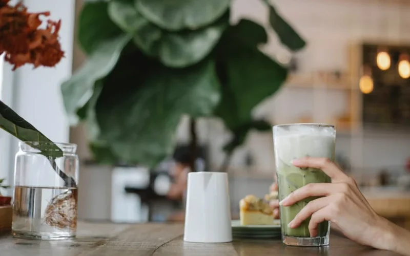 Close-up of smooth green matcha microfoam being whisked in a ceramic bowl.