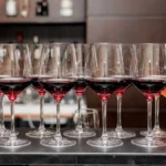 Elegant red wine in a glass next to a bottle on dark stone.