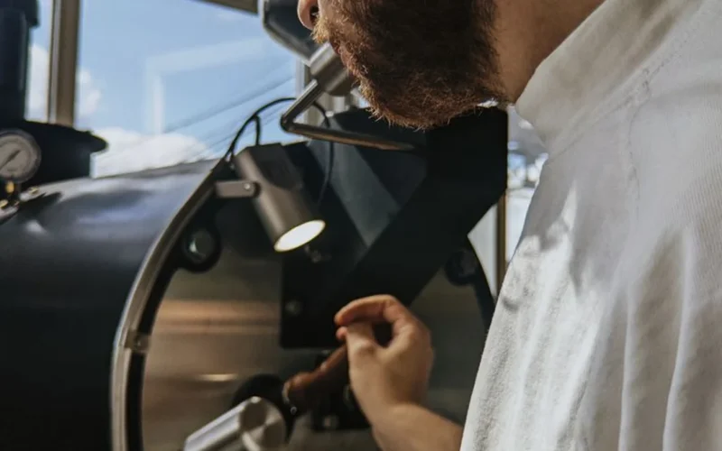 Close up of coffee beans on a digital scale with a manual grinder in a kitchen setting.