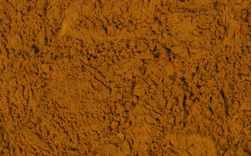Macro view of different sized coffee particle layers inside a clear glass brewing vessel.