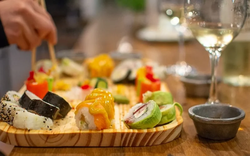 A glass of light pink Portuguese rosé wine served with fresh sushi on marble.